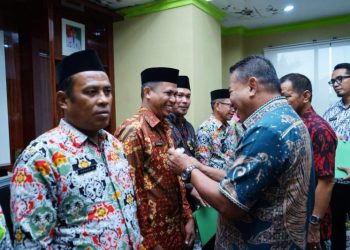 Bupati Depri Pontoh saat memakaikan Lambang Garuda kepada Pjs Sangadi (Foto : Istimewa)