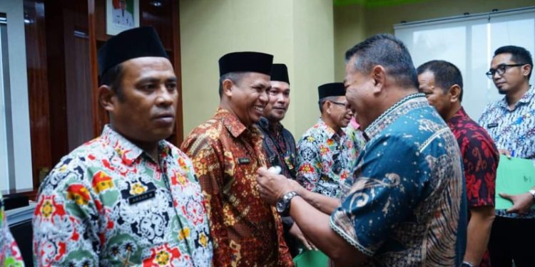 Bupati Depri Pontoh saat memakaikan Lambang Garuda kepada Pjs Sangadi (Foto : Istimewa)