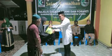 Koordinator MD KAHMI Bolmut, Dr. Arter Datunsolang, M.Si, saat menyerahkan bantuan kepada masyarakat. (Foto : Istimewa)