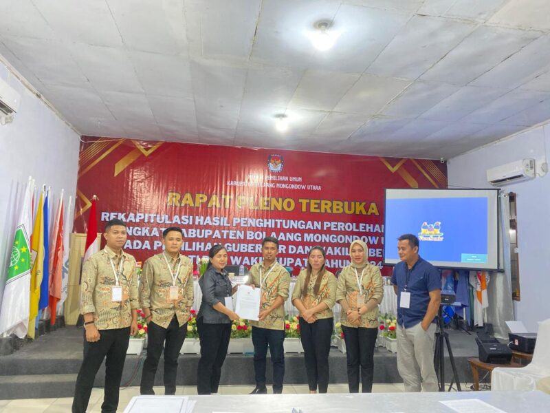 Foto : Anggota Bawaslu Bolmut, Feybe. F. Rugian, saat menerima salinan Berita Acara pada Rapat Pleno Rekapitulasi di KPUD Bolmut