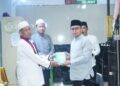 Foto : Tampak Bupati Boltara Sirajudin Lasena saat menyerahkan bantuan Al-Qur'an kepada Imam Masjid setempat