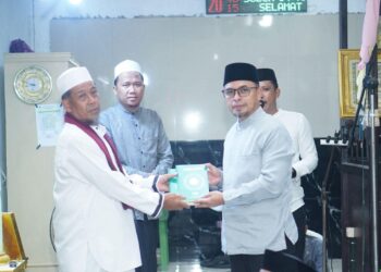 Foto : Tampak Bupati Boltara Sirajudin Lasena saat menyerahkan bantuan Al-Qur'an kepada Imam Masjid setempat