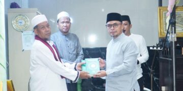 Foto : Tampak Bupati Boltara Sirajudin Lasena saat menyerahkan bantuan Al-Qur'an kepada Imam Masjid setempat