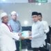 Foto : Tampak Bupati Boltara Sirajudin Lasena saat menyerahkan bantuan Al-Qur'an kepada Imam Masjid setempat
